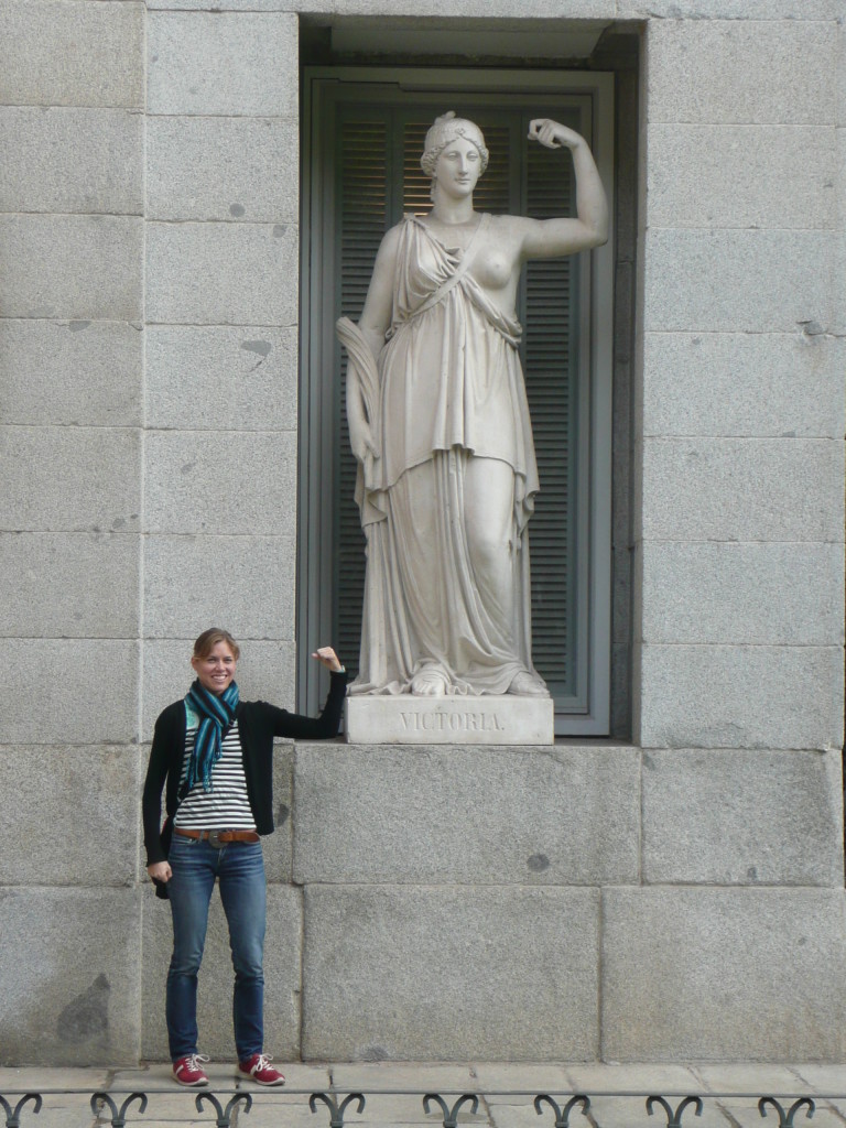 Julia flexing her large bicep like the statue, but slightly less revealingly dressed